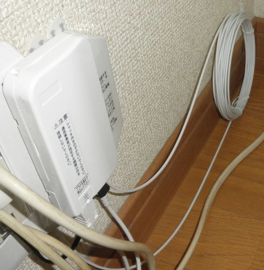 マンションの部屋に設置された光回線終端装置（ONU）と光ファイバーケーブルの写真